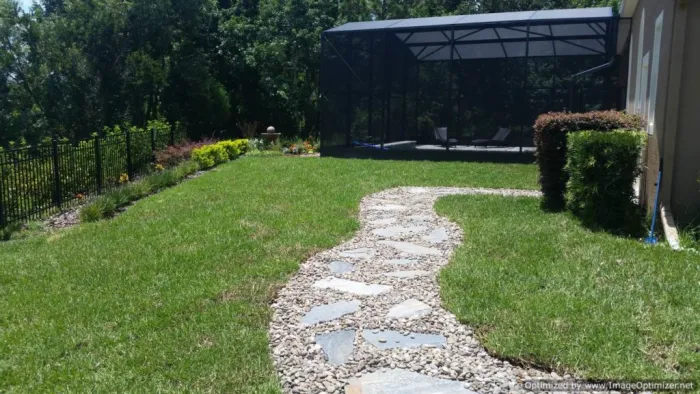 Natural grass lawn with a flagstone path toward a screened pool enclosure