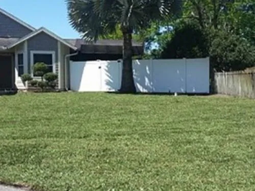 Sod lawn in front of a white vinyl privacy fence