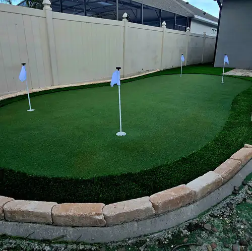 Artificial putting green with four flagged cups along a privacy fence in Sanford